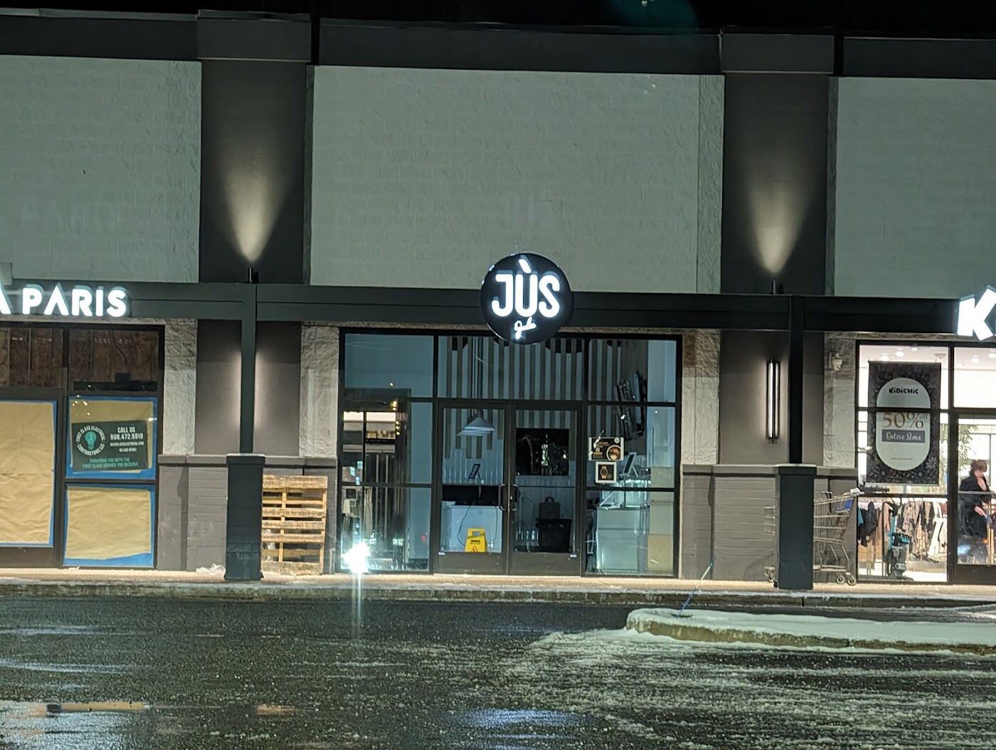 The JÙS sign on the storefront at night
