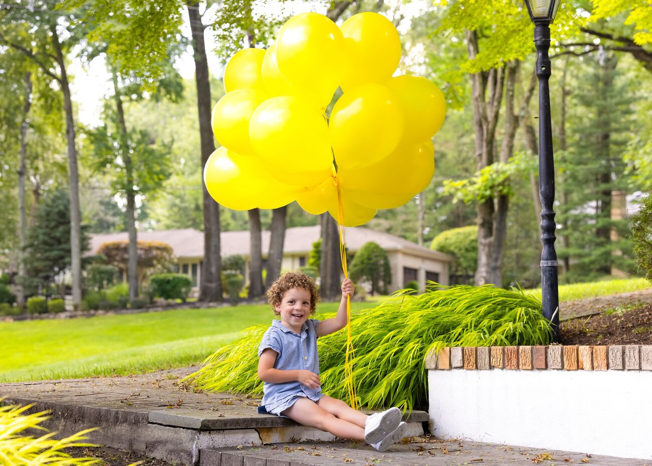 Little boy with yellow balloons in a summer garden