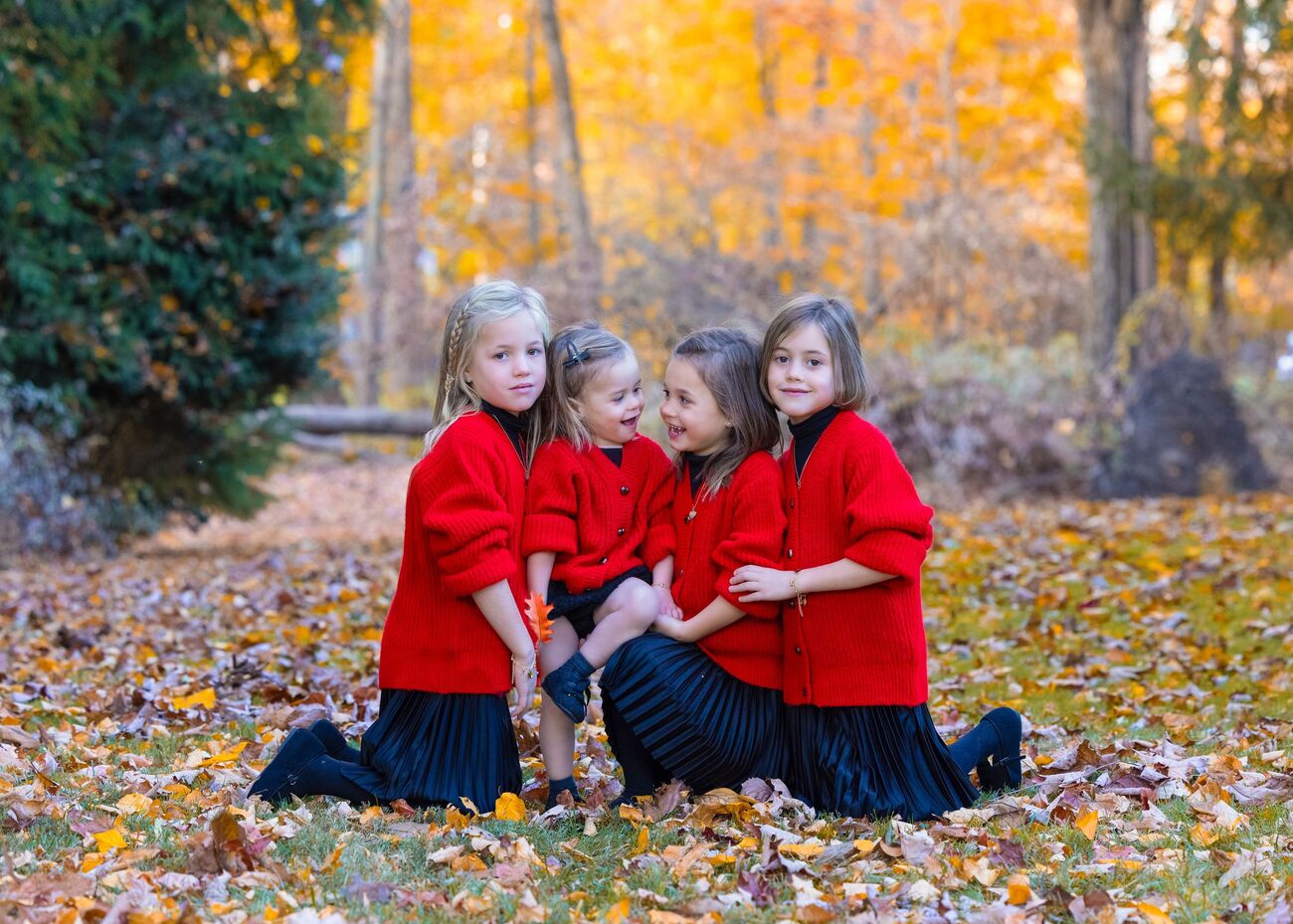 Sisters in red sitting in fall leaves